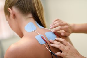 Woman receiving electrostimulation therapy for neuropathy in her neck and back